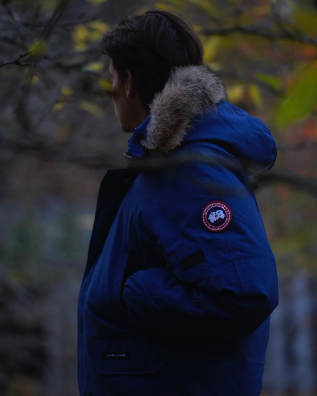 Man wearing blue Canada Goose Chilliwack bomber in a dark setting